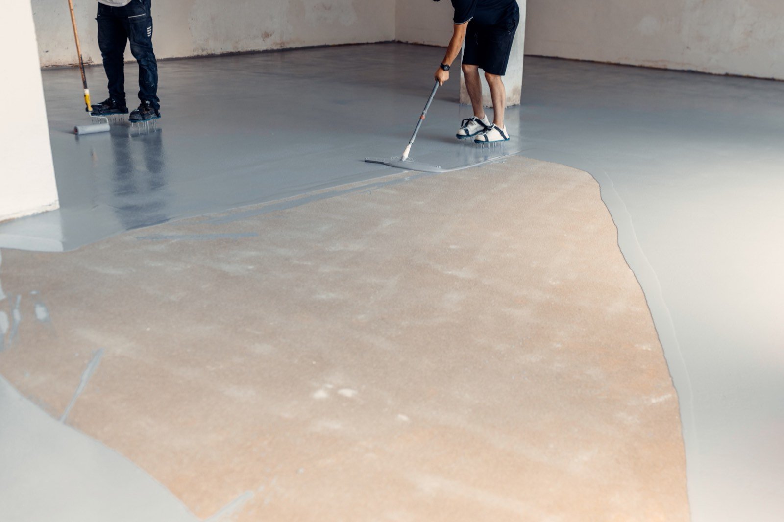Professional crew spreading and leveling a seamless floor compound in an industrial interior