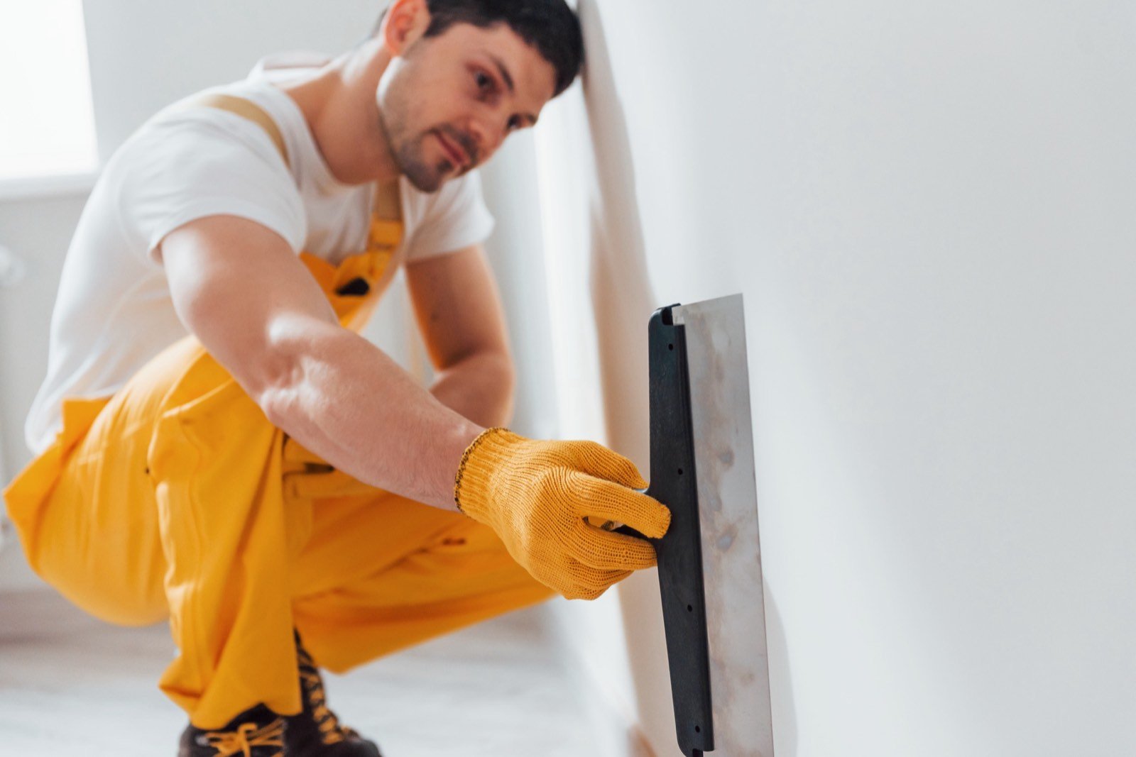 Professional plasterer screeding and leveling gypsum plaster wall
