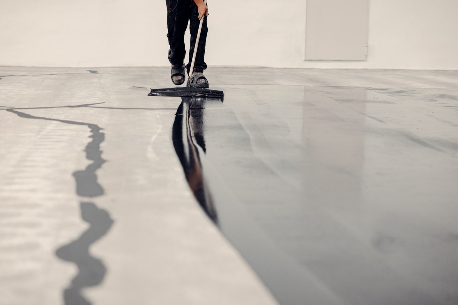 Smooth self-leveling flooring compound spreading across a floor